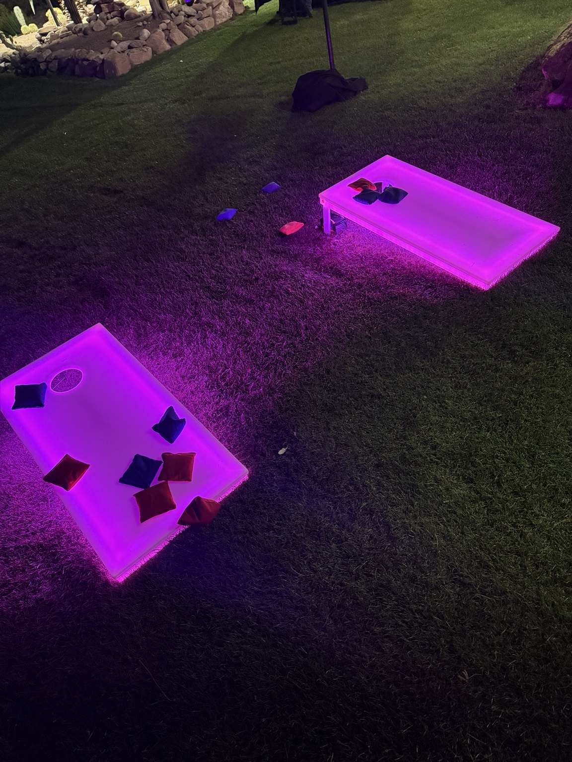 LED cornhole boards illuminated purple on a lawn